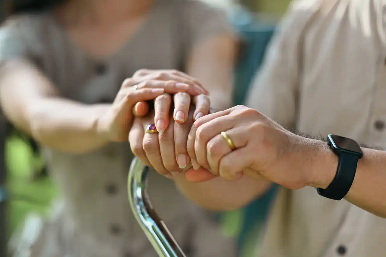 Main d’un proche soutenant une personne âgée tenant une canne, illustrant l’accompagnement et la perte d’autonomie