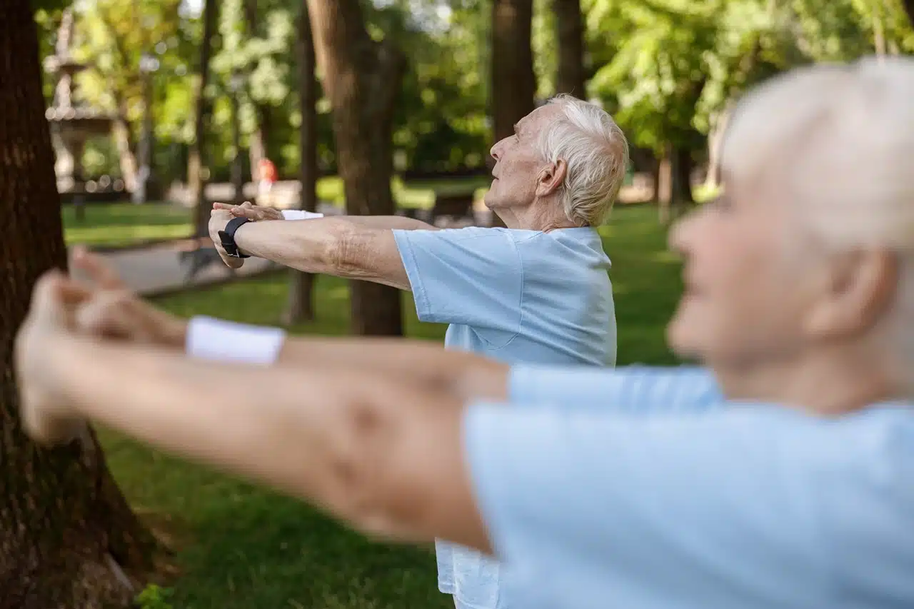 Personnes âgées faisant des exercices d'étirement dans un parc pour maintenir leur autonomie et leur mobilité