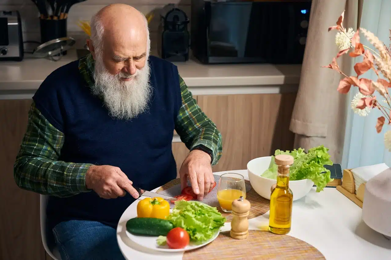 Elderly man preparing a healthy meal with fresh vegetables in his kitchen for a balanced diet