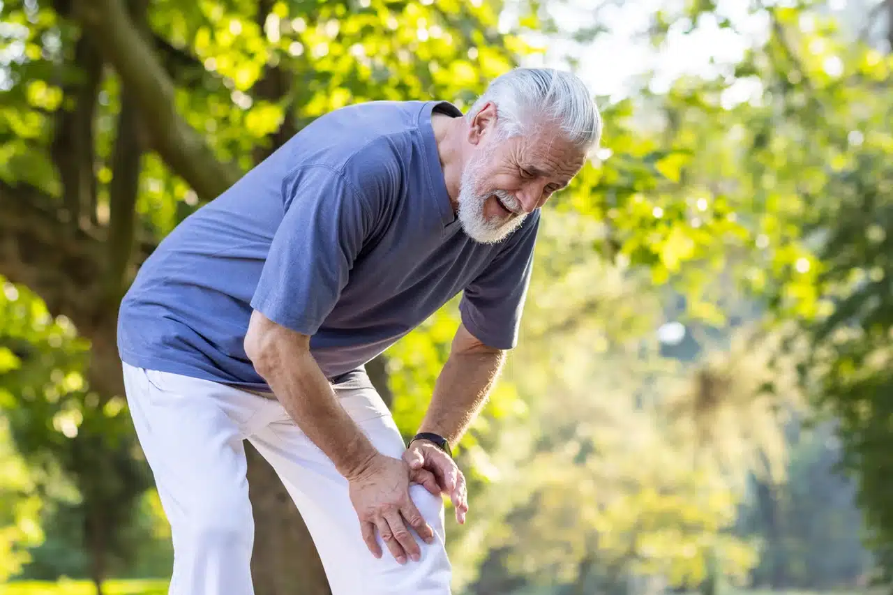 Hand gripping a wall-mounted grab bar in the bathroom to prevent falls in a person with Parkinson's disease
