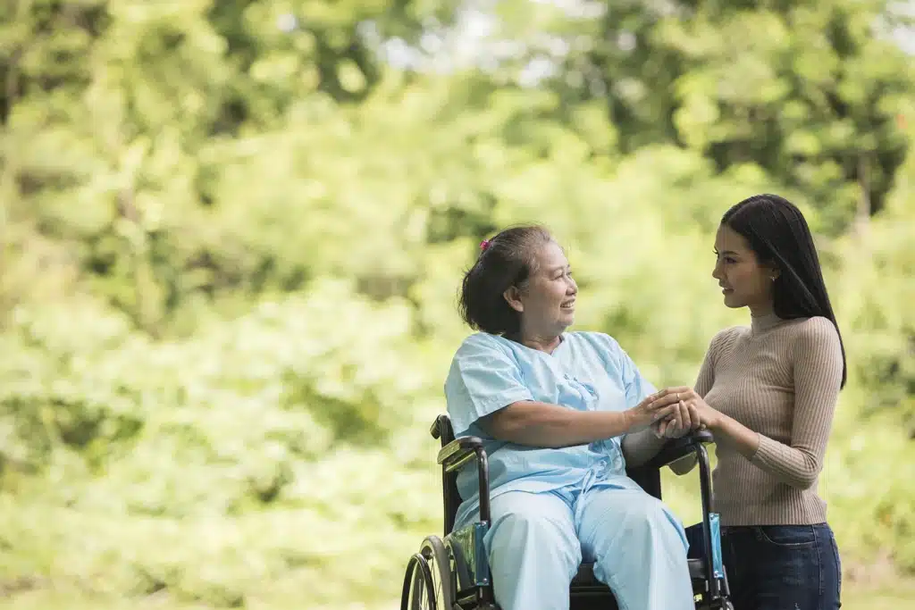 Aide-soignante soutenant l’autonomie d’une aînée en fauteuil roulant.