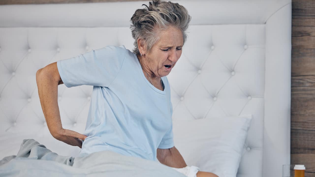 Main d'une personne âgée massant une hanche endolorie par l'arthrose